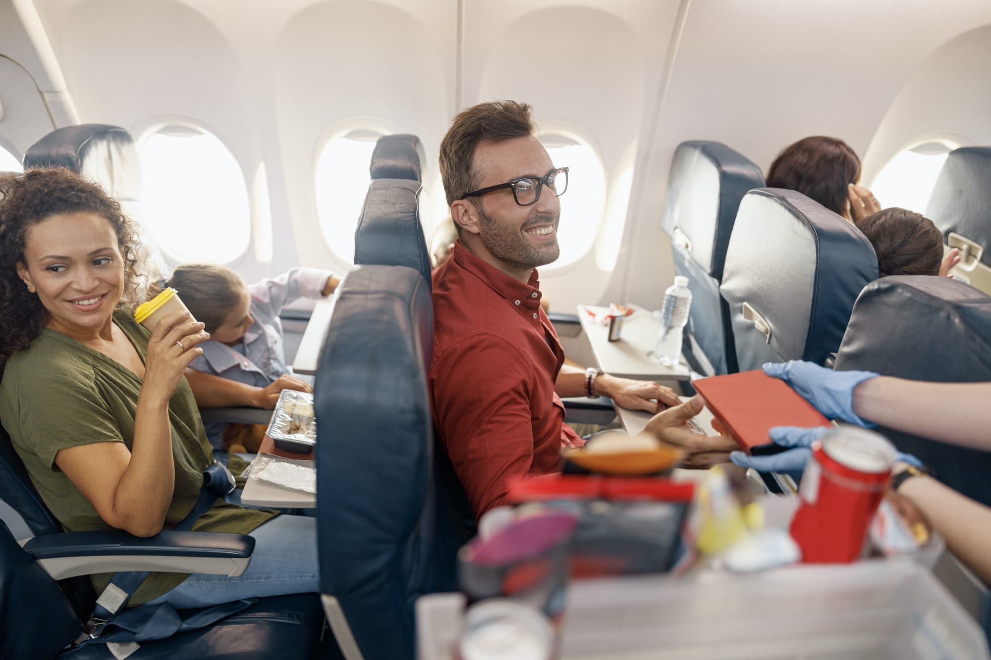 Happy passengers smiling while female flight attendant serving lunch on board